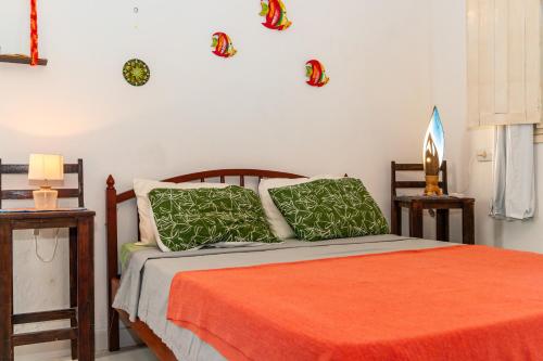 a bedroom with a bed with orange sheets and green pillows at Serrambi Praia Suites in Porto De Galinhas