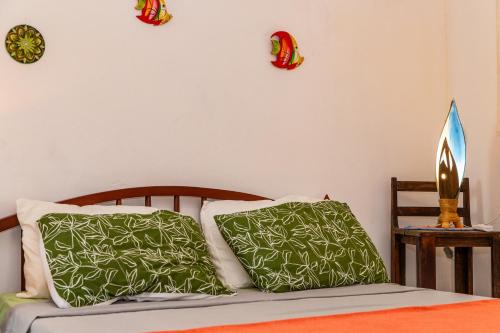 a bedroom with a bed with green and white pillows at Serrambi Praia Suites in Porto De Galinhas