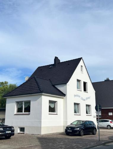 a white house with a black roof at Pension Döser Strand in Cuxhaven