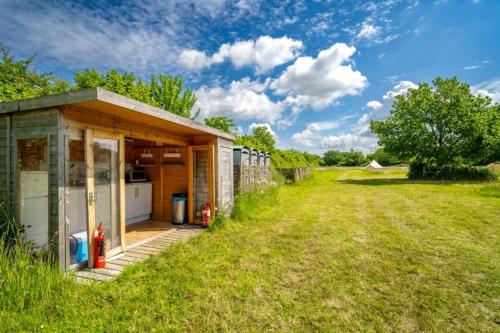 a small house in a field next to a yard at Red Clover at Blancas Bell Tents in Ringstead