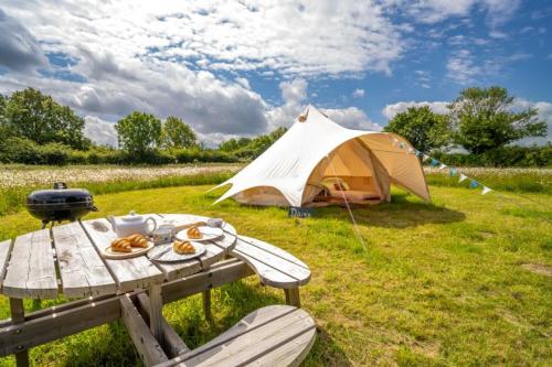 a picnic table with a tent in a field at Red Clover at Blancas Bell Tents in Ringstead