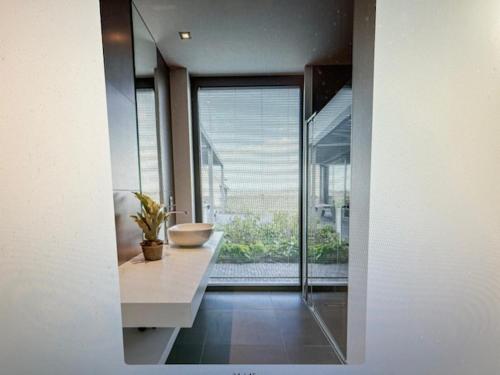 a bathroom with a sink and a large window at SCHRAVENHOEk met indoorzwembad en sauna in Veurne