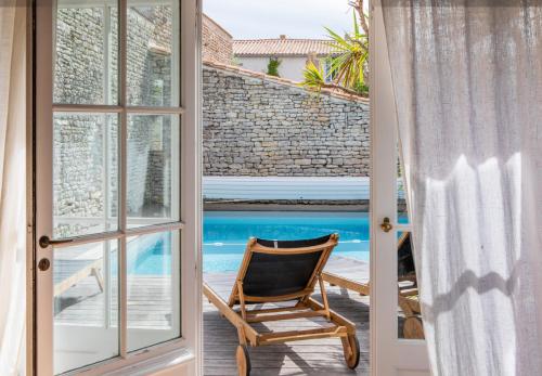une chaise assise sur une terrasse couverte avec vue sur la piscine dans l'établissement Île de Ré - 9 personnes - Plage à pieds - Piscine, à Saint-Clément-des-Baleines