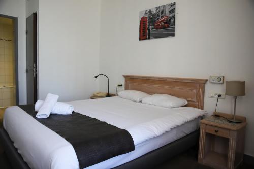 a bedroom with a bed with white sheets and pillows at Brit Hotel Aux Sacres Reims, Centre Historique in Reims