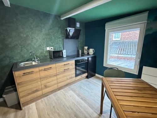 a kitchen with a sink and a table and a window at Suite Tropical-Netflix-Parking in Douai
