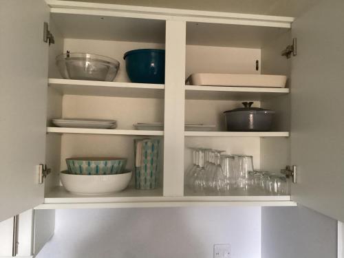 a kitchen shelf with bowls and other dishes on it at Scalpay@Knock View Apartments, Sleat, Isle of Skye in Teangue