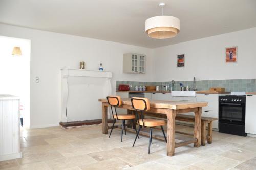 une cuisine avec une table et des chaises en bois dans l'établissement Maison typique avec jardin, 5km de la plage, à Plévenon