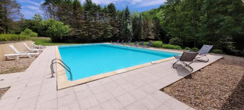 - une piscine avec 2 chaises et un ordinateur portable à côté dans l'établissement Grande maison pour 8 - Tranquillité - Piscine, à Saint-Paul-la-Roche