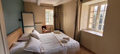 une chambre avec un lit avec des draps blancs et des oreillers dans l'établissement Grande maison pour 8 - Tranquillité - Piscine, à Saint-Paul-la-Roche