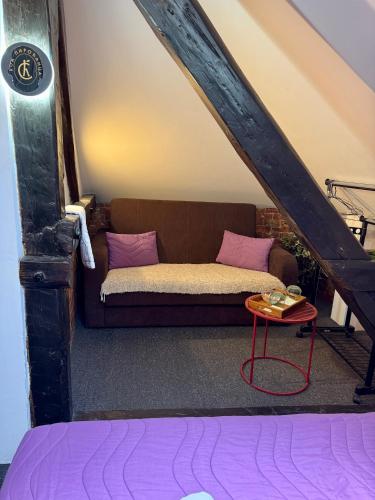 a couch with pink pillows and a table in a attic at Pirocanac Hotel rooms & restaurant in Pirot