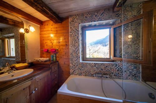 une salle de bain avec une baignoire, un lavabo et une fenêtre dans l'établissement Maison atypique de montagne, à Brides-les-Bains