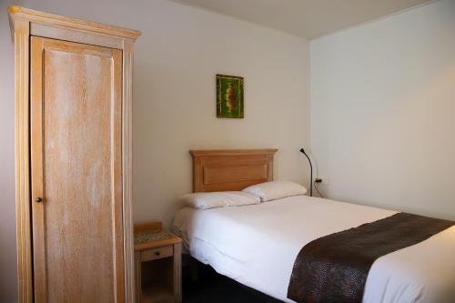 a small bedroom with a bed and a wooden cabinet at Brit Hotel Aux Sacres Reims, Centre Historique in Reims