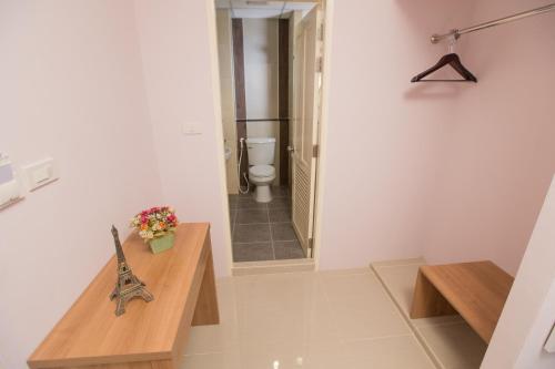 a bathroom with a toilet and a wooden table at The Bedroom Ladprao 101 Bangkok - SHA in Bangkok
