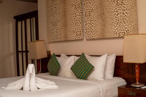 a bedroom with a bed with white sheets and pillows at NIKARA Luxury Beach House in Tissamaharama