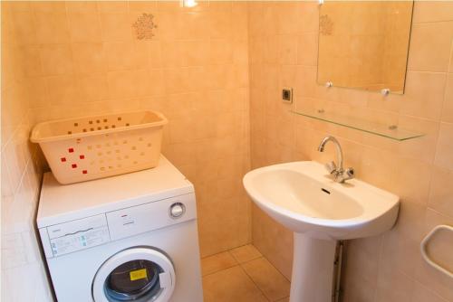 une salle de bain avec une machine à laver et un lavabo dans l'établissement Location a chanteperdrix 2 personnes, à Sainte-Énimie