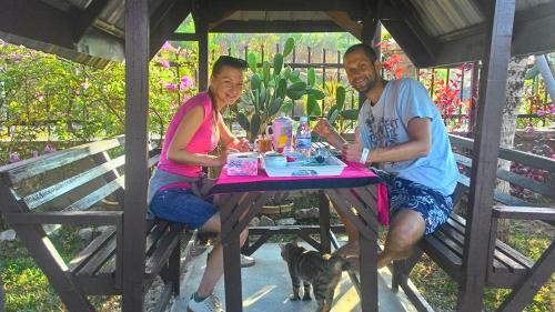 un hombre y una mujer sentados en una mesa de picnic en Pemandangan Indah Guest House - Look Out Point Villa-, en Pantai Cenang