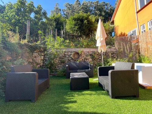 a yard with chairs and an umbrella and grass at Retiro das Águas - Gerês in Terras de Bouro