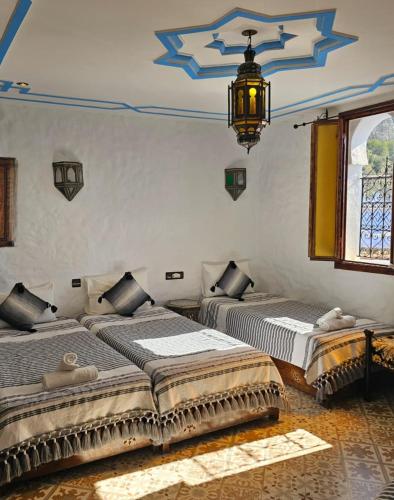 2 Betten in einem Zimmer mit Kronleuchter in der Unterkunft Dar Yakout in Chefchaouen