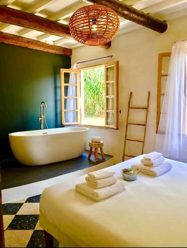 La salle de bains est pourvue d'une baignoire et d'un lit avec des serviettes. dans l'établissement Villa Charme avec Piscine privée au coeur des Vignes, à Quarante