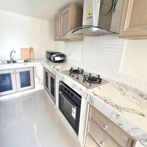 a white kitchen with a stove and a sink at Perfect Home 15 mins from airport in Chiang Mai