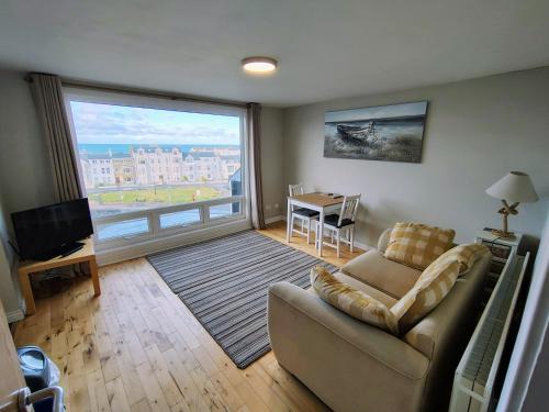 a living room with a couch and a large window at The Loft Guest Apartment in Portstewart