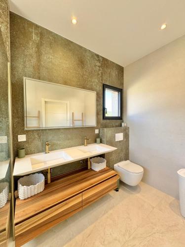 une salle de bain avec un lavabo, des toilettes et un miroir dans l'établissement Villa Porto-Vecchio avec piscine, à Lecci