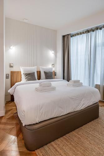 une chambre avec un grand lit avec des draps blancs dans l'établissement Typical Parisian Apartment in Le Marais#4 pers, à Paris