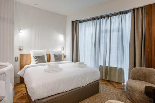 une chambre avec un grand lit blanc et une chaise dans l'établissement Typical Parisian Apartment in Le Marais#4 pers, à Paris