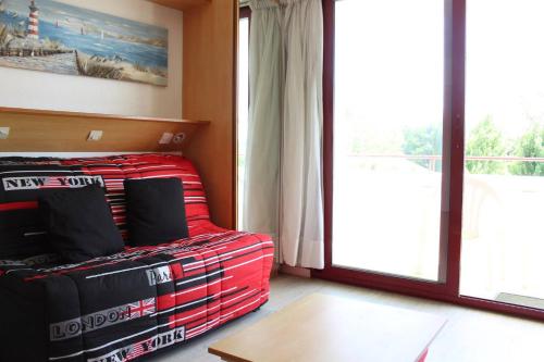 Cette chambre dispose d'un canapé rouge et d'une grande fenêtre. dans l'établissement Studio LA ROCHELLE - LR010-205, à La Rochelle