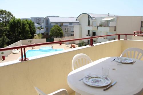 d'une table et de chaises blanches sur un balcon avec piscine. dans l'établissement Studio LA ROCHELLE - LR010-205, à La Rochelle