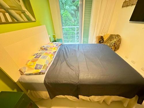 ein großes Bett in einem Zimmer mit Fenster in der Unterkunft Guaratuba 2 sobrado cinematográfico próximo da praia in Bertioga
