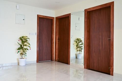 two wooden doors in a room with two potted plants at LeafyInn Premium 2BHK Apartment-Khanapara in Guwahati