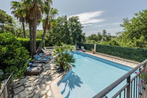 une piscine avec chaises longues et palmiers dans l'établissement 7 bedrooms Villa in St Paul de Vence with 5000sqm, à Vence