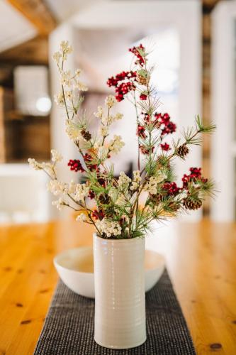 a white vase with red flowers on a table at Lodge 67°N Lapland in Äkäslompolo