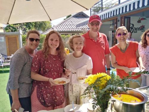 a group of people standing around a table with food at Bronte BnB in Cha Am