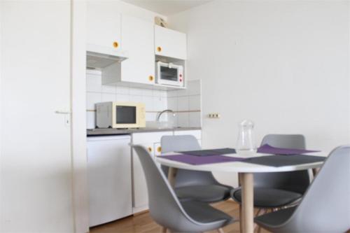 une cuisine avec une table et des chaises dans une pièce dans l'établissement Appt Studio cabine LA ROCHELLE - LR190-201, à La Rochelle