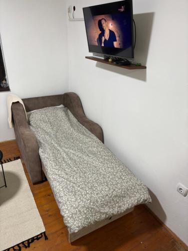 a couch in a room with a tv on a wall at Kutak Sreće in Vrdnik