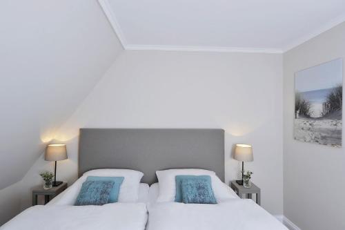 two beds in a bedroom with white walls and blue pillows at Bahnhofstraße 22B in Keitum