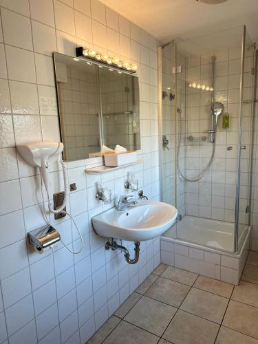 a white bathroom with a sink and a shower at Hotel Hofmann Zur Mühle in Bad Krozingen