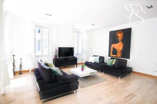 - un salon avec deux canapés noirs et une télévision dans l'établissement Renovated 3 bedrooms with patio - heart of Cannes, à Cannes