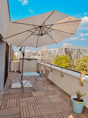 d'une terrasse avec un parasol et des chaises sur le balcon. dans l'établissement Superbe Appartement ,Terrasse avec climatisation et parking payants, à Bagneux