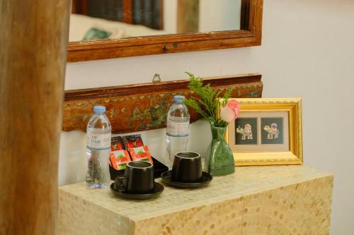 a table with cups and a picture and a mirror at Charm Vân Long in Ninh Binh