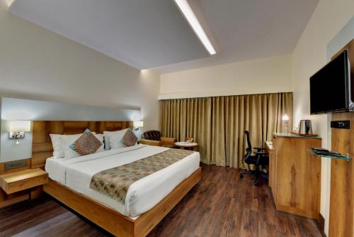 a hotel room with a bed and a television at The Luxant Hotel in Bengaluru