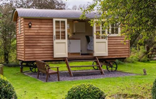 a large wooden cabin with a bench in a yard at Shepherds Hut at Snowdon Farm in Badger