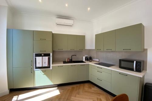 La cuisine est équipée de placards blancs et d'un four micro-ondes noir. dans l'établissement New apartment in Forville with balcony, à Cannes