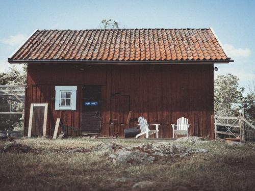 a red house with two white chairs in front of it at Folk och Fä in Grisslehamn