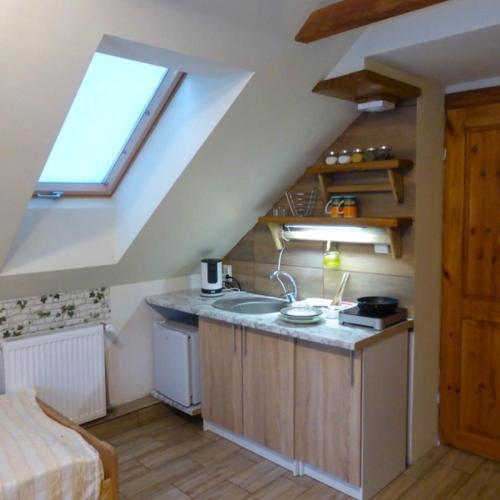 an attic kitchen with a sink and a window at Aktywna Agroturystyka in Stare Jabłonki