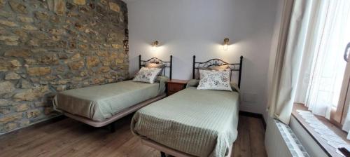 two beds in a room with a stone wall at Caserio EL AJO in Herrán