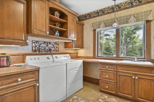 a kitchen with a white dishwasher and wooden cabinets at Lake Breeze Luxury Executive Retreat in Three Lakes