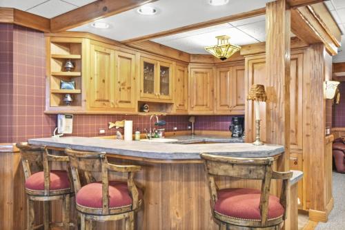 a kitchen with wooden cabinets and a island with bar stools at Lake Breeze Luxury Executive Retreat in Three Lakes